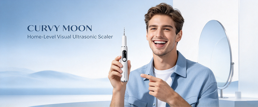 Smiling man holding a white Curvy Moon handheld tooth cleaner beside a round bathroom mirror.