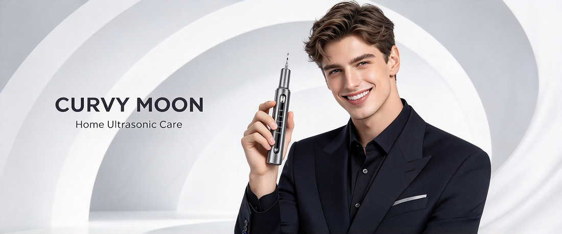 Smiling man in a dark suit holding a Curvy Moon handheld ultrasonic tooth cleaner against a light gray background.