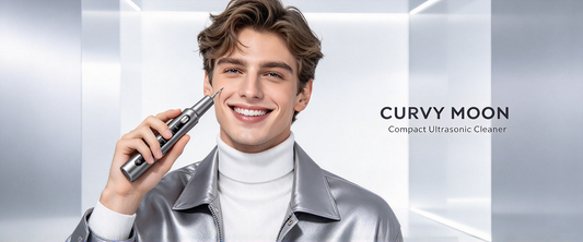 Smiling man in a silver jacket holding a gray Curvymoon handheld tooth cleaner beside his face.